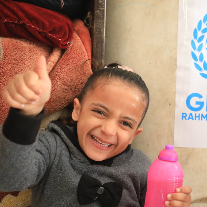 child smiling and standing in front of GRF Gaza water tank