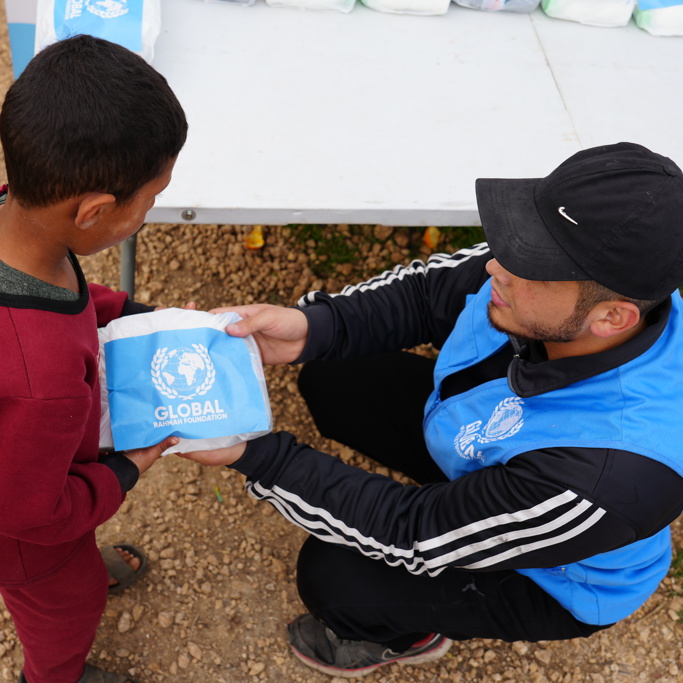 Global Rahmah Foundation representative handing aid to a child in Lebanon