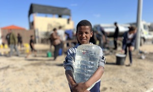 young boy holding a container of water in Gaza 2025