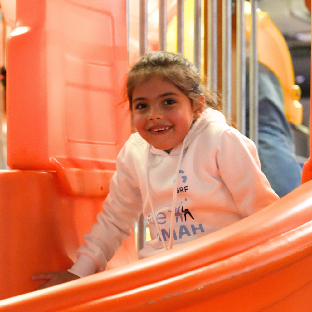 young child smiling while playing on slide Lebanon 2025