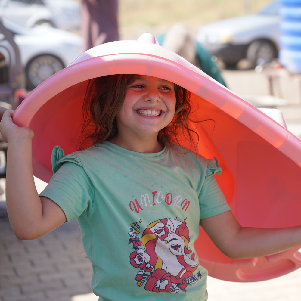child smiling as holding bath tub from mother and baby kit