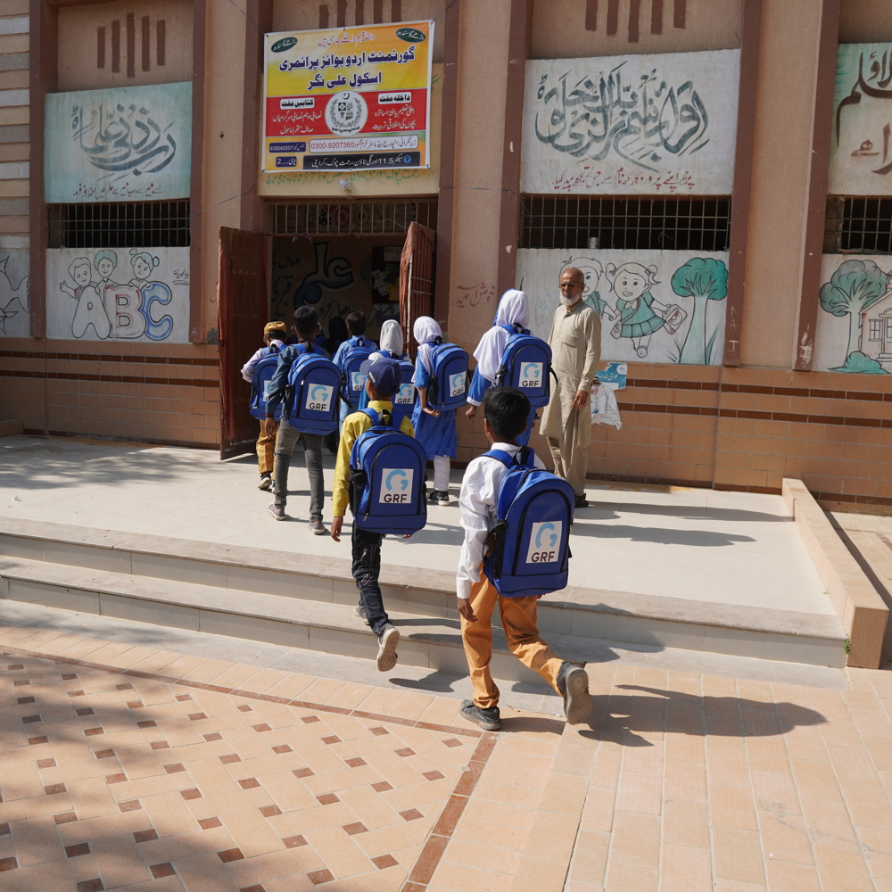 children in Pakistan walking wearing blue school bags from GRF